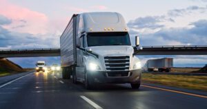 White semi-truck driving on highway at dusk